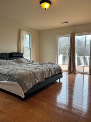 A spacious bedroom with a large bed, a ceiling light, and a view of the outdoors through a sliding glass door. - Lake Anna Waterfront, Private Pool&Spa, Game Room, Pickle Ball, Tiki, Fire pit (Orange)