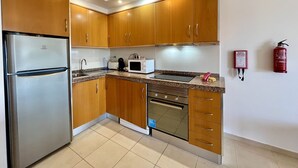 A kitchen with wooden cabinets, stainless steel appliances, a microwave, and a fire extinguisher.