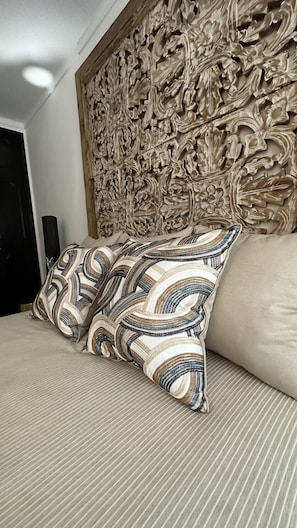 A bed with striped bedding and two patterned pillows.
