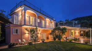 A two-story house with a balcony, outdoor seating area, and a well-maintained garden.