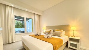 Une chambre d’hôtel avec un grand lit, deux tables de chevet, une fenêtre avec des rideaux et une vue sur l’extérieur.