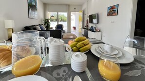 A dining area with a table set for breakfast, including fruits, a pitcher, and a glass of orange juice. - Vilamoura Club Villa 3 by Homing (Loulé)