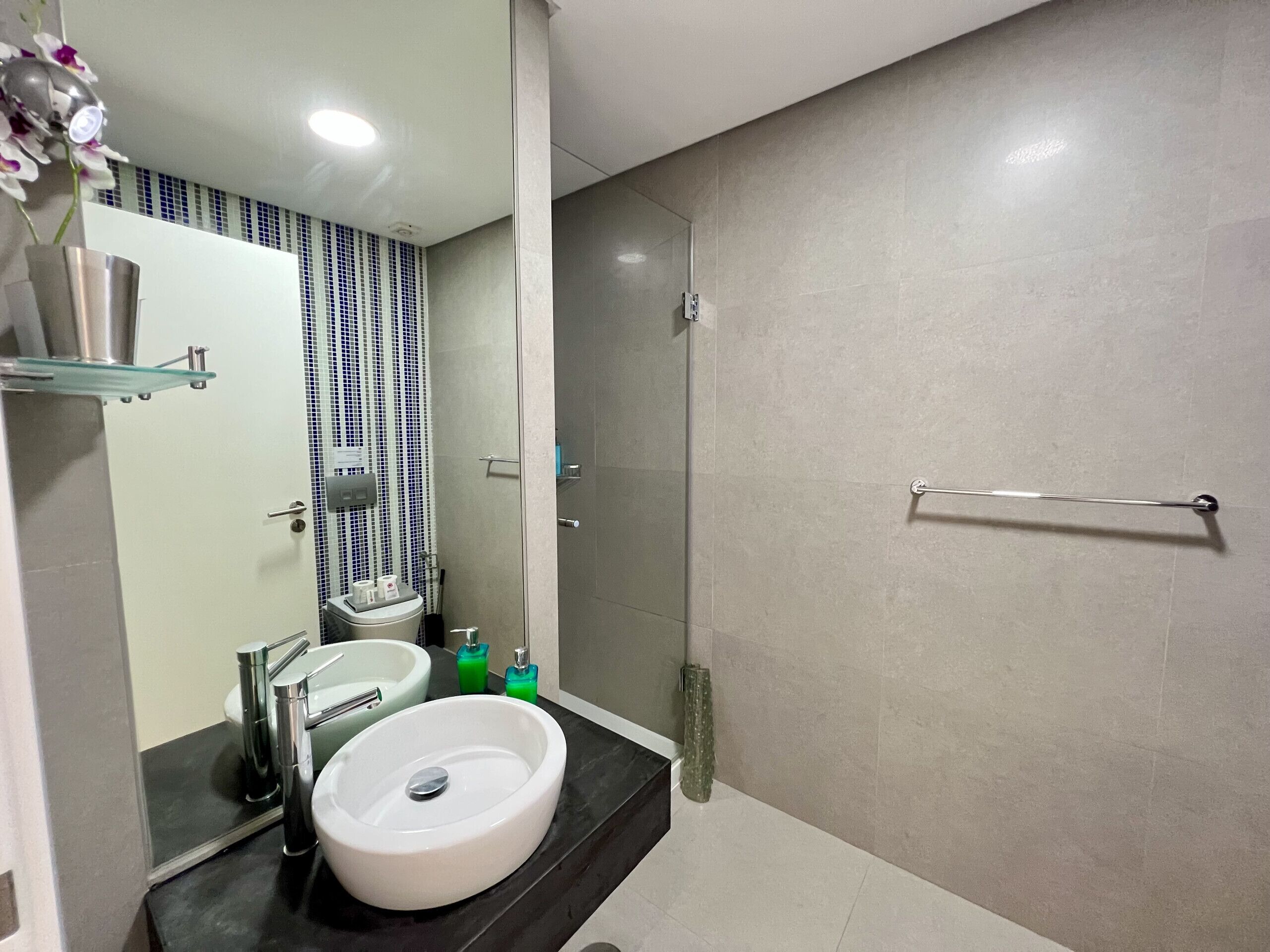 Un bagno moderno con un lavandino bianco, un box doccia in vetro e un porta asciugamani.