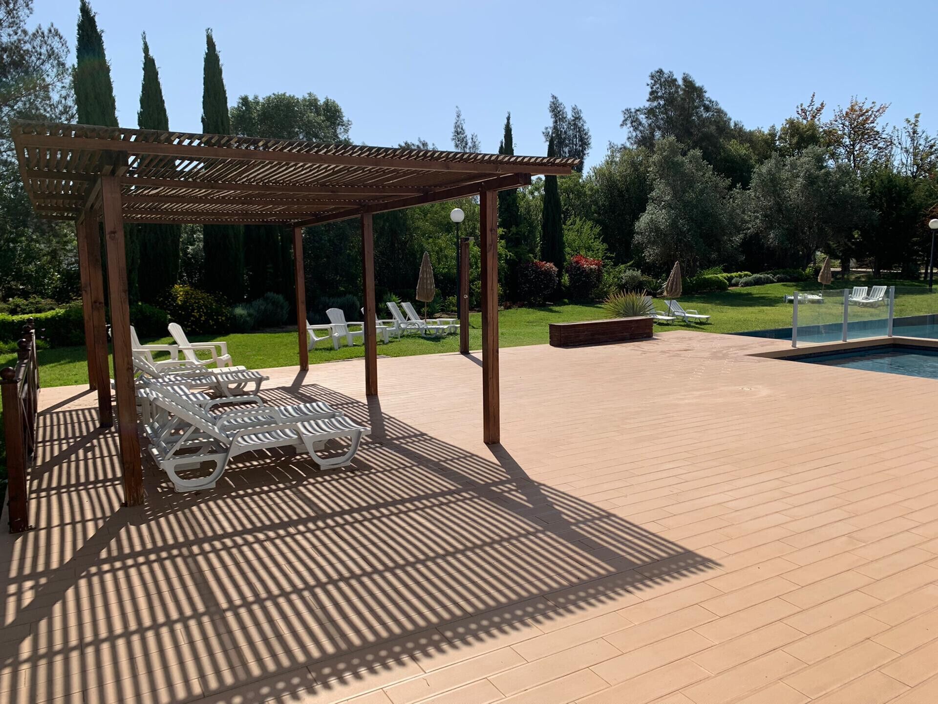 Un espacio al aire libre techado con piscina, sillones de descanso y una pérgola.