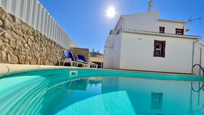A swimming pool with clear blue water, surrounded by stone walls and a white building with a red window. - Pêra Stylish Villa With Pool by Homing (Silves)