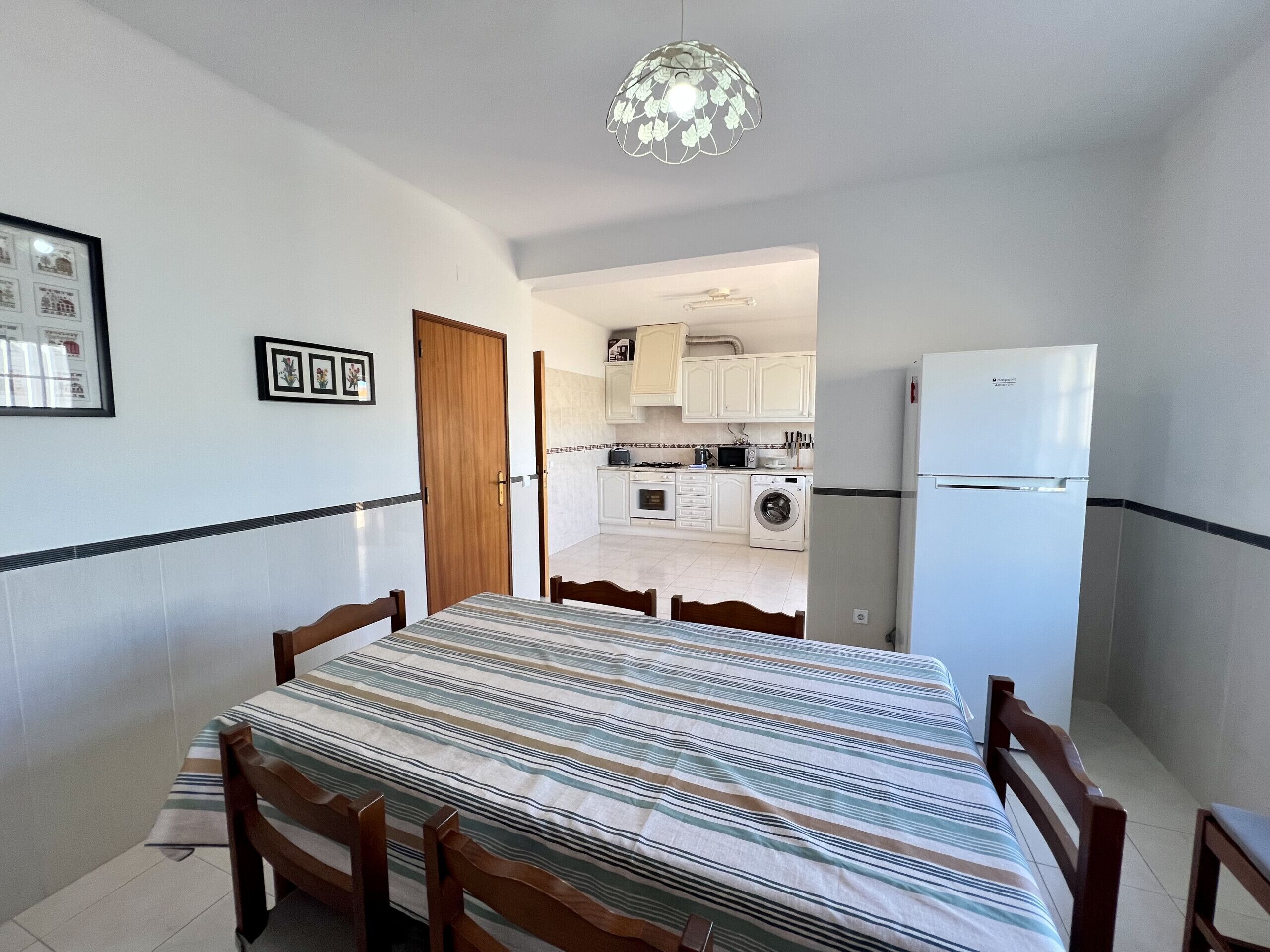 A compact kitchen with white cabinets, a washing machine, and a refrigerator.