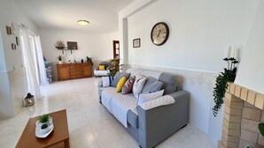 A living room with a grey sofa, wooden cabinet, and a clock on the wall. - Pêra Stylish Villa With Pool by Homing (Silves)