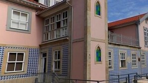 A building with a pink facade, blue patterned windows, and a tower with a green window. - PALÁCIO NOVA  SEARA  2503 -AL (Armamar)