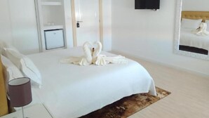 A hotel room with a large bed, a flat-screen TV mounted on the wall, a door, and a small bedside table with a lamp. - PALÁCIO NOVA  SEARA  2503 -AL (Armamar)