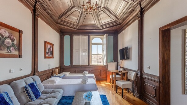 A spacious living room with a large sofa, a coffee table, and a view of the city through a large window. - PALÁCIO NOVA  SEARA  2503 -AL (Armamar)