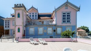 A pink and blue tiled building with a balcony and lounge chairs. - PALÁCIO NOVA  SEARA  2503 -AL (Armamar)