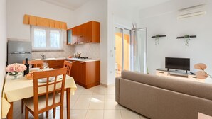 Eine moderne Küche mit Holzausstattung, einem Esstisch mit Stühlen und einer Wohnbereich mit Sofa und Fernseher.