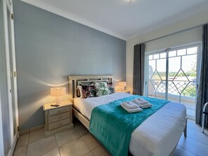 A hotel room with a bed, two bedside tables with lamps, a window with curtains, and a view of the outside. - Vilamoura Deluxe Villa by Homing (Loulé)