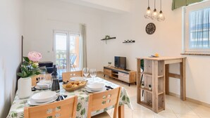 A dining area with a table set for two, a television, and a wooden side table. - Affordable apartment with stylish interior, baby crib, playground (Vodnjan)