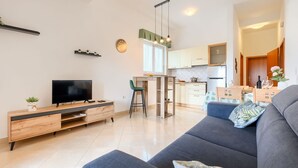 A modern living room with a TV, sofa, and dining area. - Affordable apartment with stylish interior, baby crib, playground (Vodnjan)