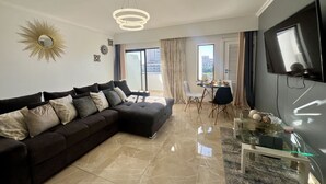 Una sala de estar moderna con un sofá seccional, un comedor y un televisor montado en la pared.