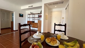 Un'area pranzo allestita per la colazione, con piatti di frutta, croissant e succo di frutta.
