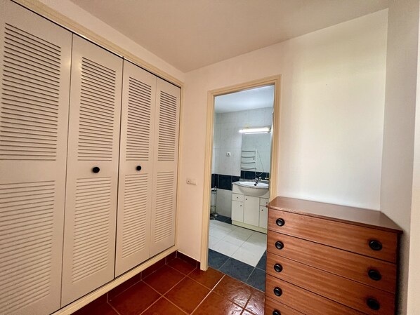 Un pasillo con un aparador de madera y una puerta de armario con espejo.