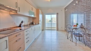 A modern kitchen with a granite countertop, stainless steel appliances, and a dining area with a table and chairs. - Lagos Palm Tree 1 With Pool by Homing (Lagos)