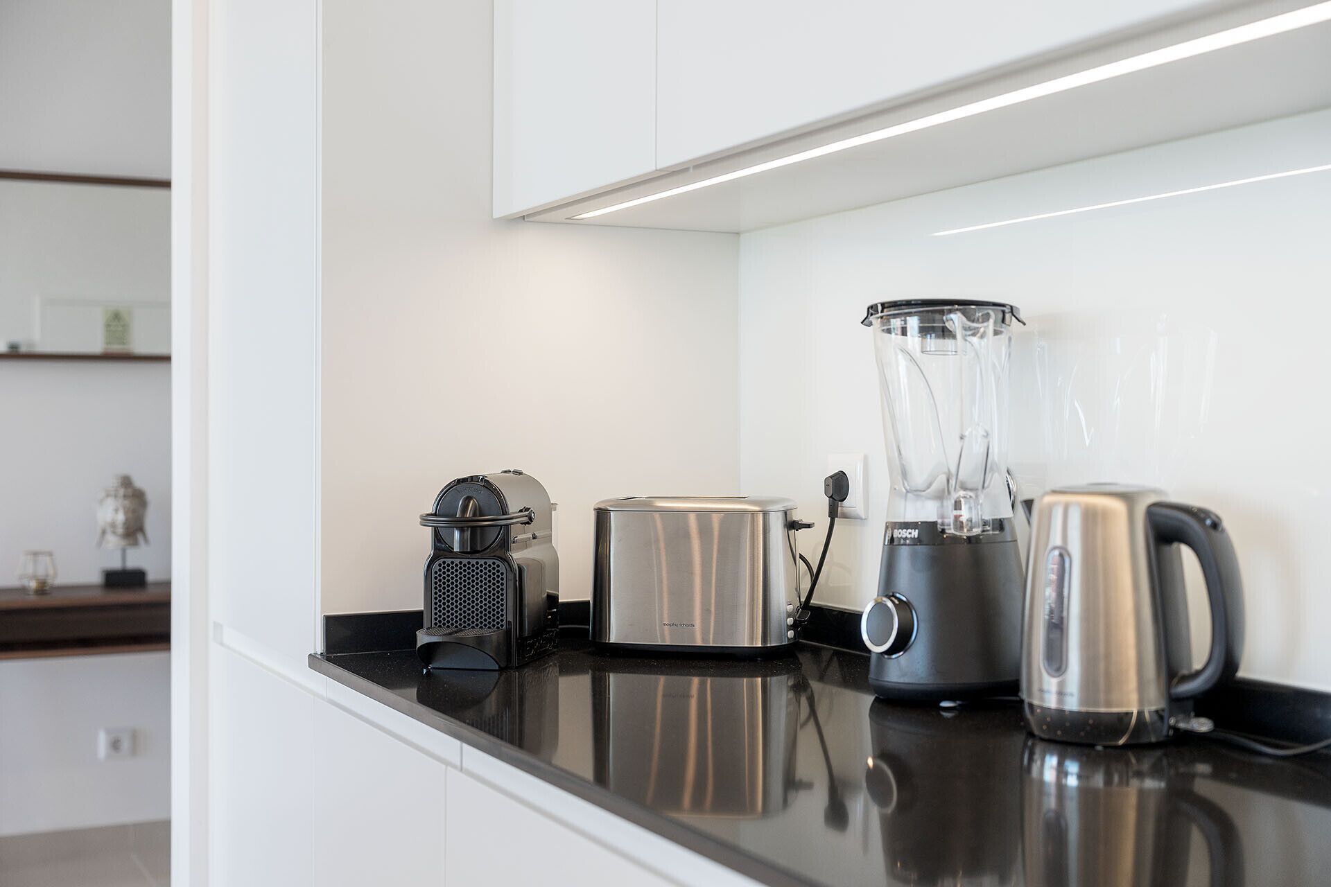 A kitchen counter with a toaster, a blender, and a kettle.