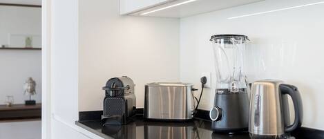 A kitchen counter with a toaster, a blender, and a kettle.
