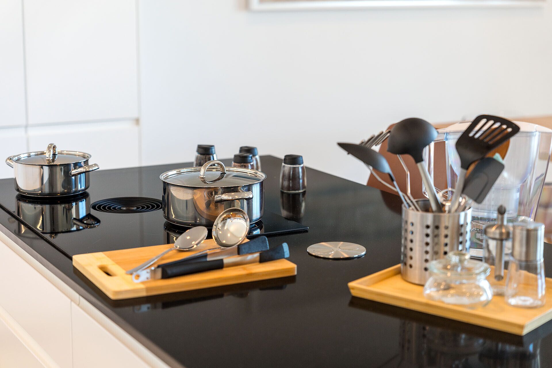 A kitchen counter with stainless steel pots, a stove, and various kitchen utensils.