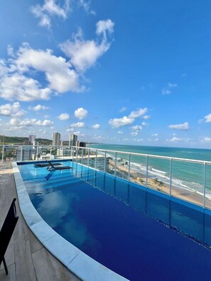 A rooftop infinity pool with a view of the ocean and beach. - Rn Studio Apto 510 (Maceió)