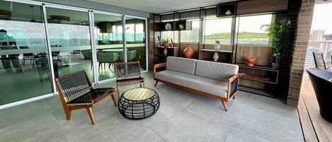 Una sala de estar moderna con un sofá, sillas y una mesa redonda. Hay un balcón con vistas a la ciudad.