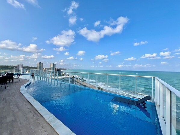 A rooftop infinity pool with a view of the ocean and city skyline. - Rn Studio Apto 510 (Maceió)