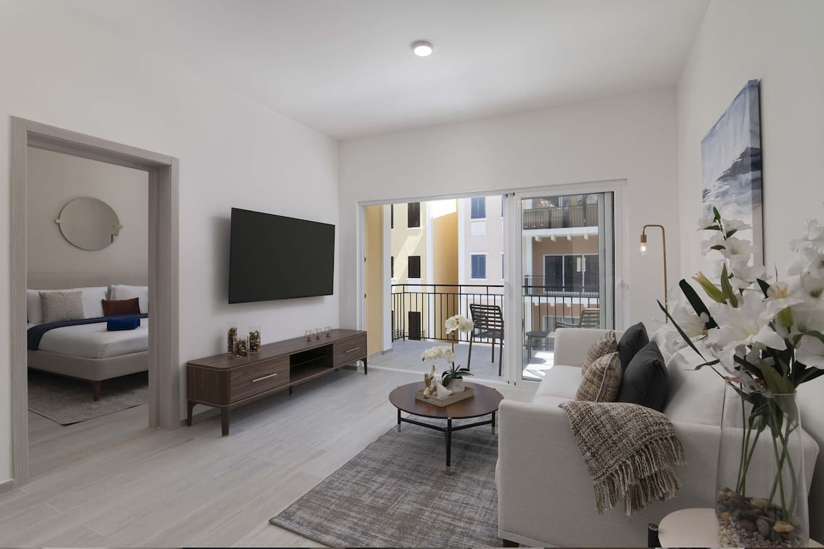A modern living room with a sofa, coffee table, and a flat-screen TV mounted on the wall.