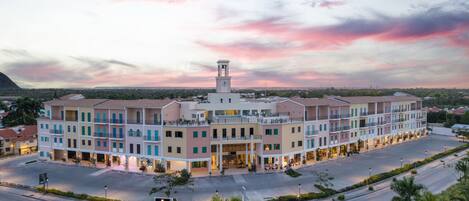 A multi-story hotel with a central tower, surrounded by a landscaped area with palm trees.