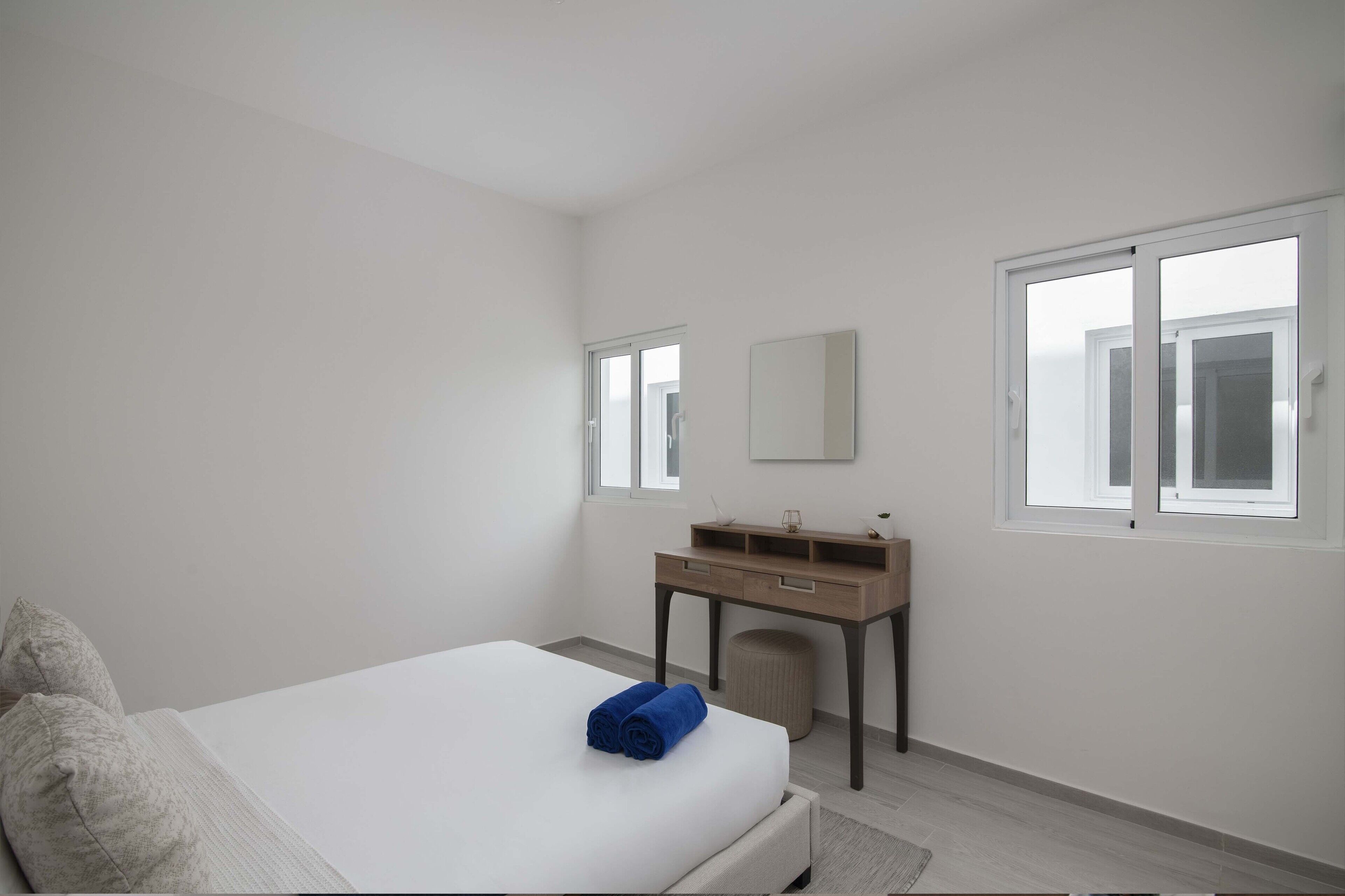 A bedroom with a bed, a desk, a chair, and a window.