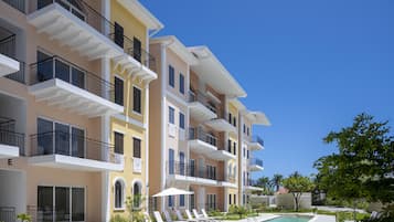 Un hôtel à plusieurs étages doté de balcons, d’une piscine et de chaises longues.