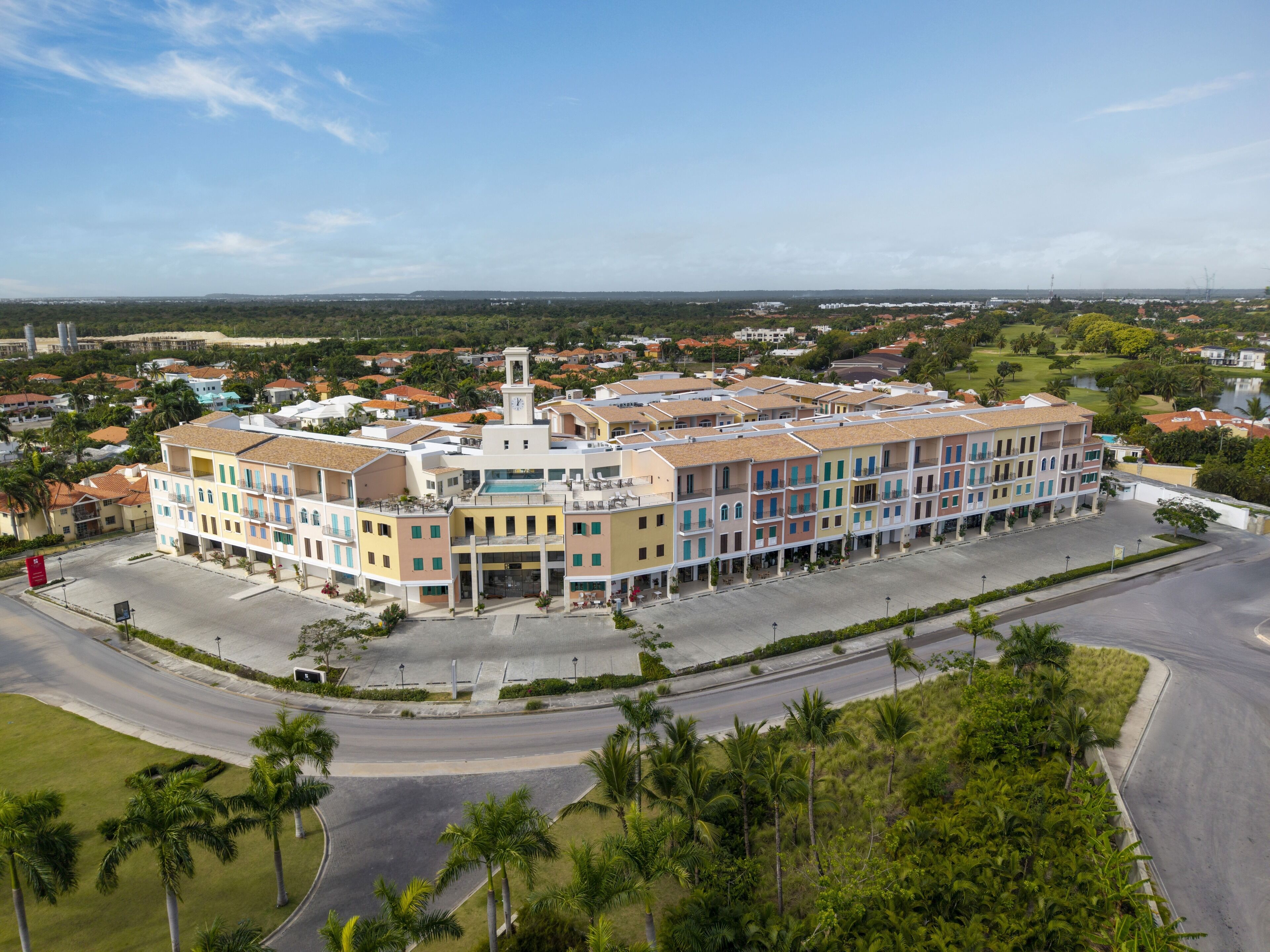 A multi-story hotel with a central courtyard, surrounded by palm trees and a view of the cityscape.