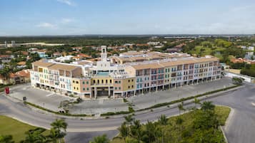 A multi-story hotel with a central courtyard, surrounded by palm trees and a view of the cityscape.
