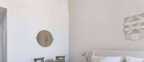 Une chambre d’hôtel comprenant un lit, un élément de décoration circulaire fixé au mur, une petite table avec des chaises, une lampe de chevet et un pouf rond.