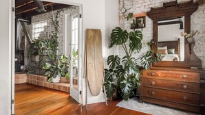 A room with a wooden dresser, a large mirror, and a potted plant.