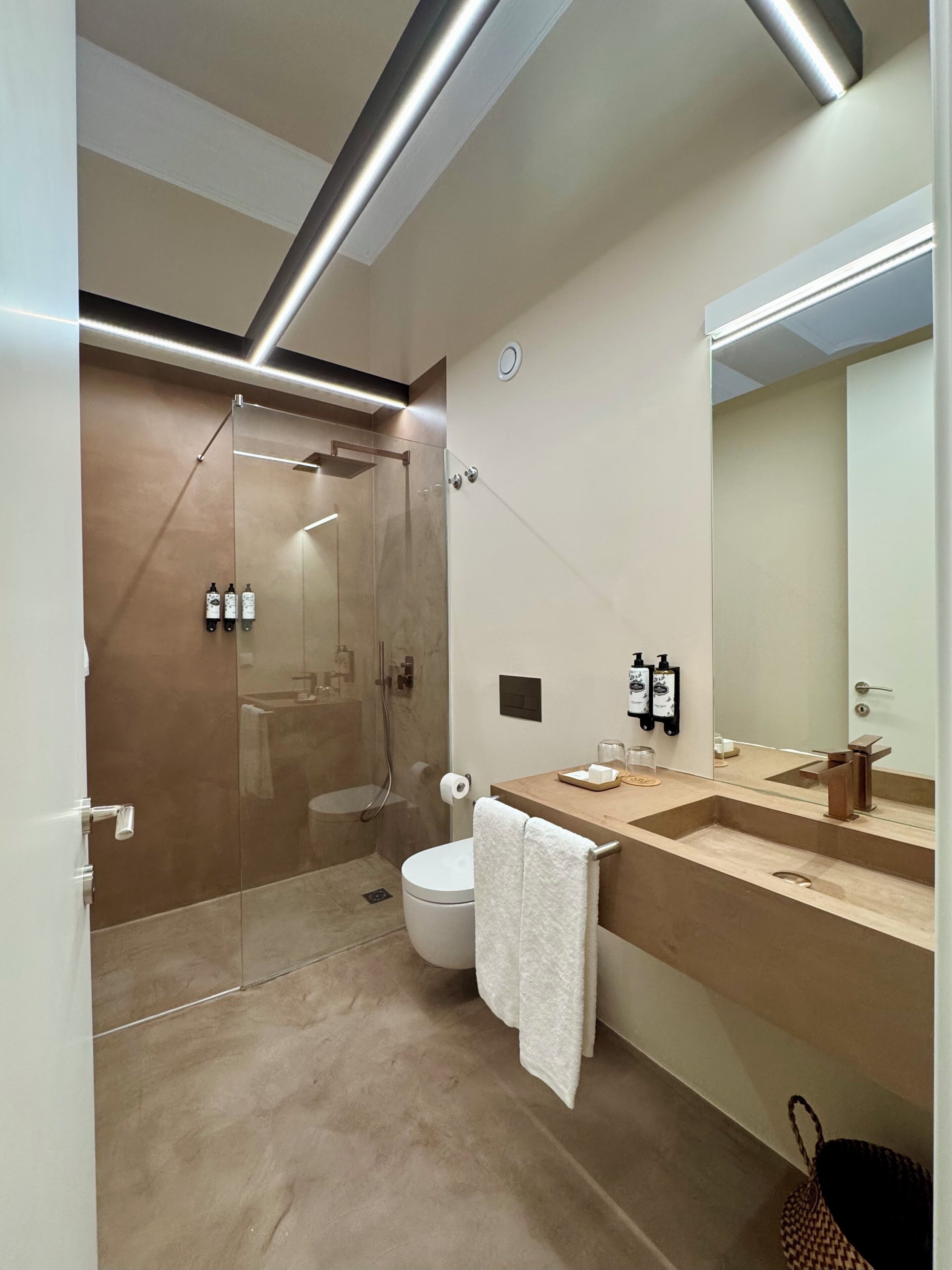 Un baño moderno con ducha envuelta en vidrio, inodoro y tocador con espejo.