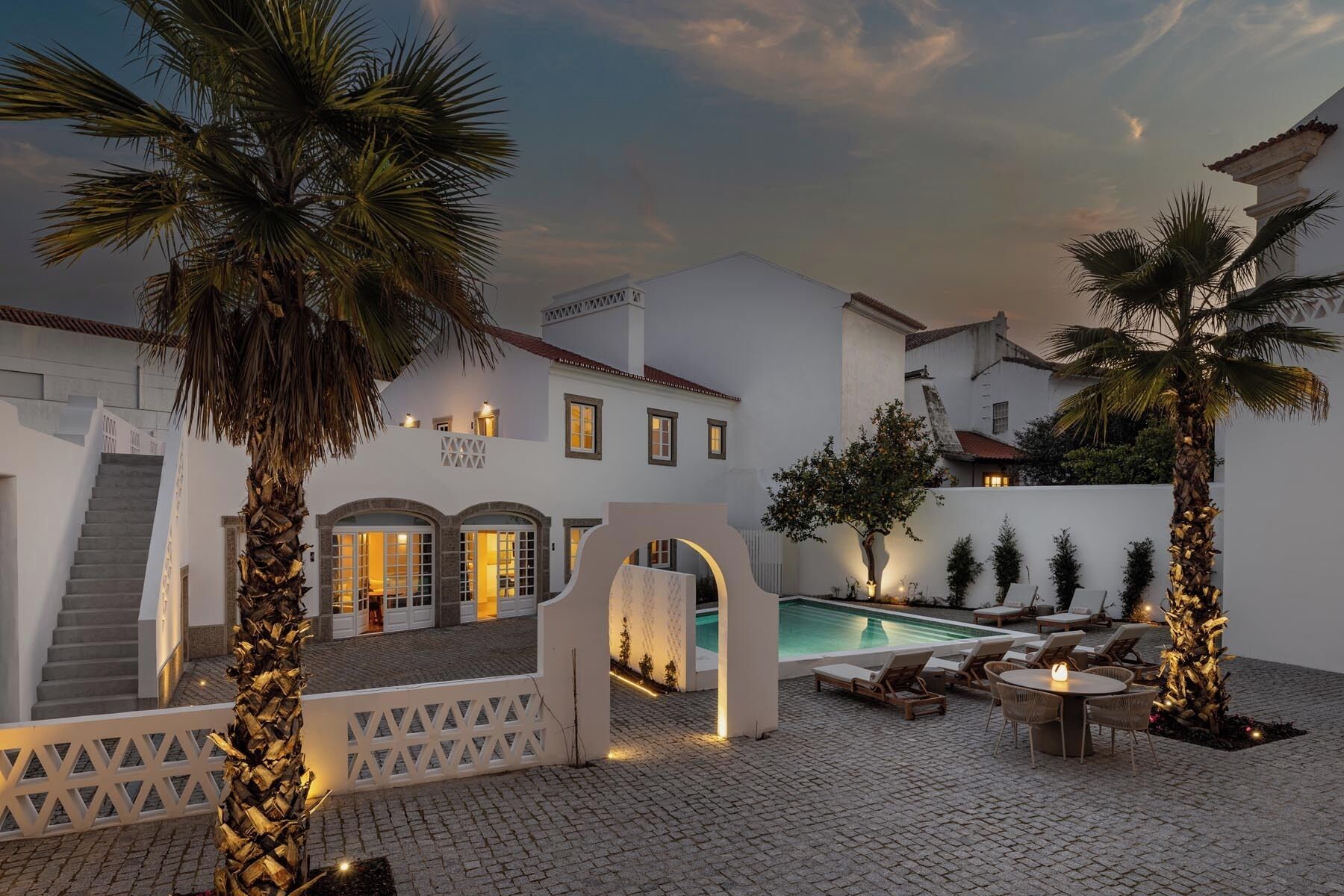 Un patio con piscina, palmeras y una escalera que conduce a un edificio.