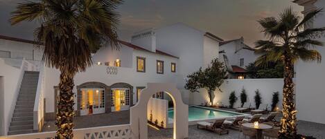 Un patio con piscina, palmeras y una escalera que conduce a un edificio.
