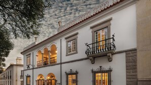 A historic building with arched doorways, a balcony with wrought iron railings, and a cobblestone street. - CICIOSO Boutique Hotel (Évora)
