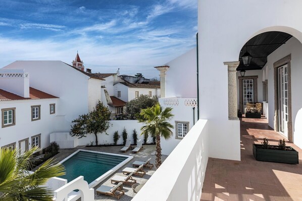 A courtyard with a swimming pool, lounge chairs, and a view of surrounding buildings. - CICIOSO Boutique Hotel (Évora)