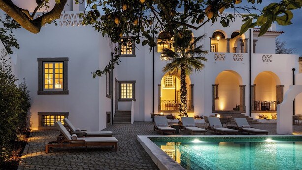 A poolside area with lounge chairs, a tiled pool, and a building with arched doorways and windows. - CICIOSO Boutique Hotel (Évora)