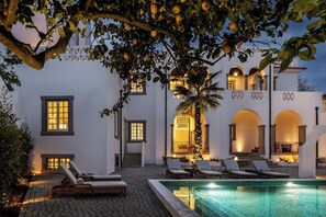 A poolside area with lounge chairs, a tiled pool, and a building with arched doorways and windows. - CICIOSO Boutique Hotel (Évora)