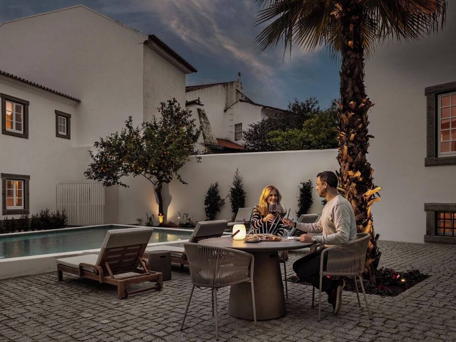 A poolside area with a table and chairs, a pool, and a palm tree.