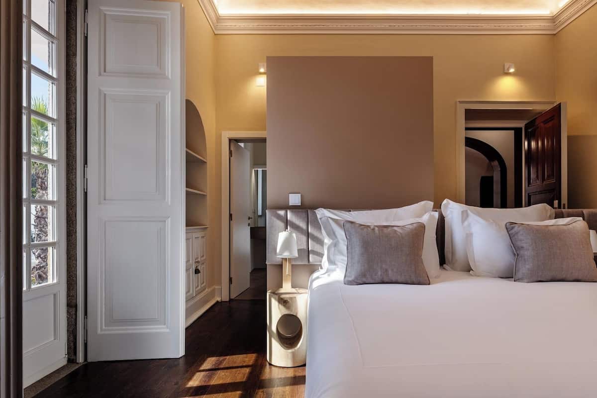 Habitación de hotel con una cama grande, una lámpara de noche y vistas al pasillo.