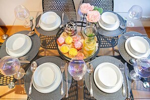Mesa dispuesta para seis personas, con platos, cubiertos y vasos, rodeada de sillas.