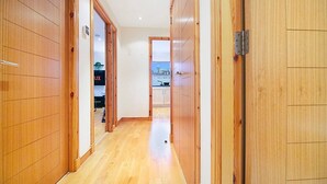 Un pasillo con paneles de madera y vista a una habitación con zona de cocina.