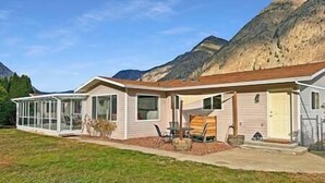Una casa a un piano con veranda coperta, garage e montagne sullo sfondo.