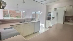 Una cucina moderna con mobili bianchi, un lavello in acciaio inossidabile e una finestra che si affaccia su un muro in mattoni.